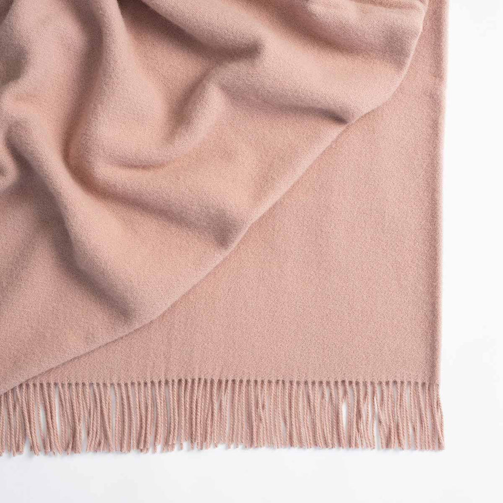 A lambswool throw blanket in a soft pink hue. 