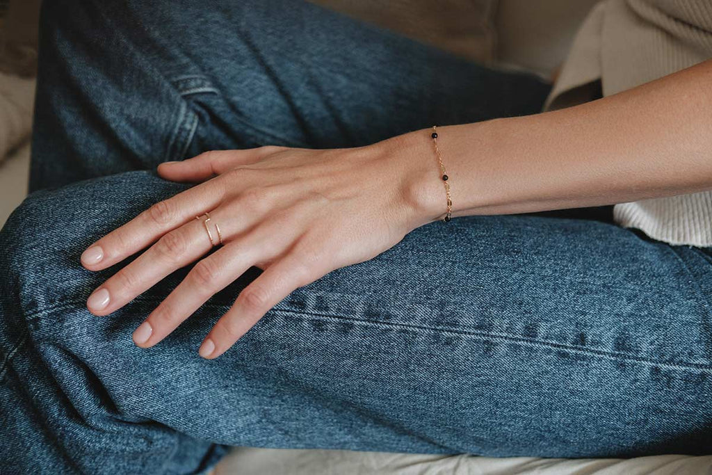 A woman wearing a gorgeous delicate and sophisticated gold-fill chain style bracelet with black agate beads