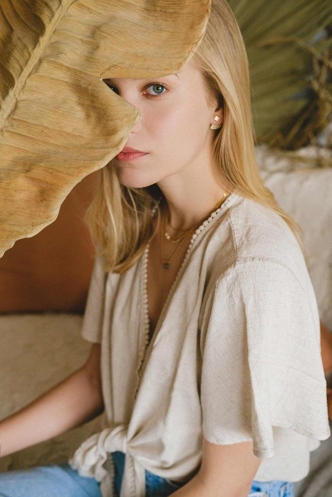 A woman wearing the China square stud earrings, with the jacket behind her earlobe. 