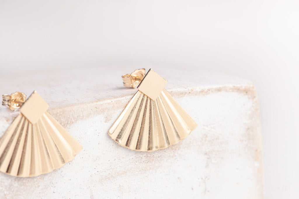 The China stud earrings in yellow-gold fill by Zoaje, with square studs and pleated jackets. 