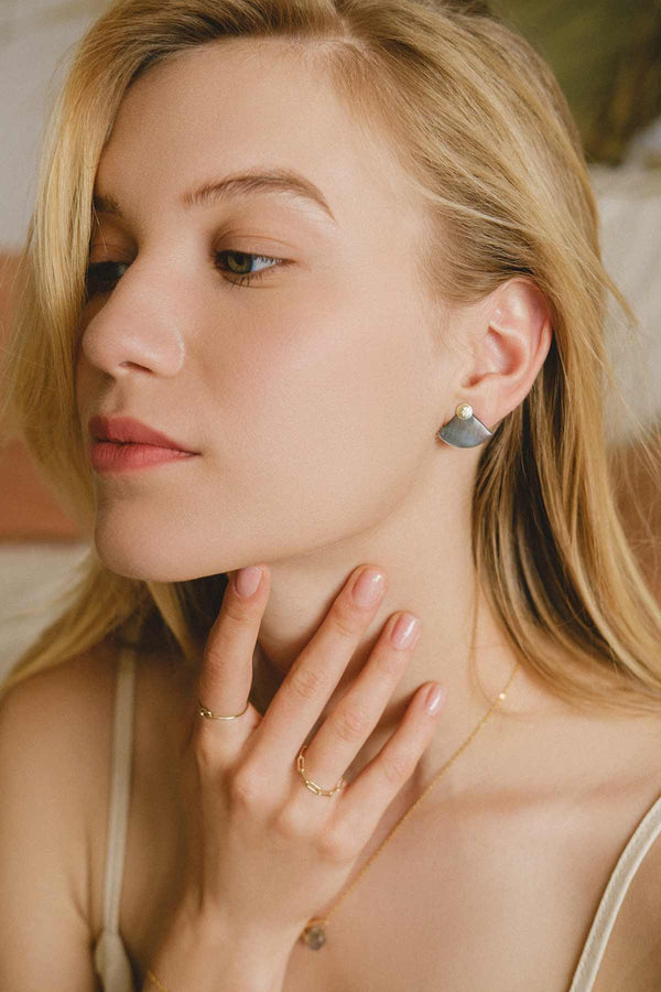 A woman wearing the Laos earrings in one of three ways. The Mother-of-pearl jacket is placed in front of her ear, highlighting the natural grey tones of the beautiful shell. 