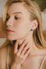 A woman wearing the Laos earrings in one of three ways. The Mother-of-pearl jacket is placed in front of her ear, highlighting the natural grey tones of the beautiful shell. 