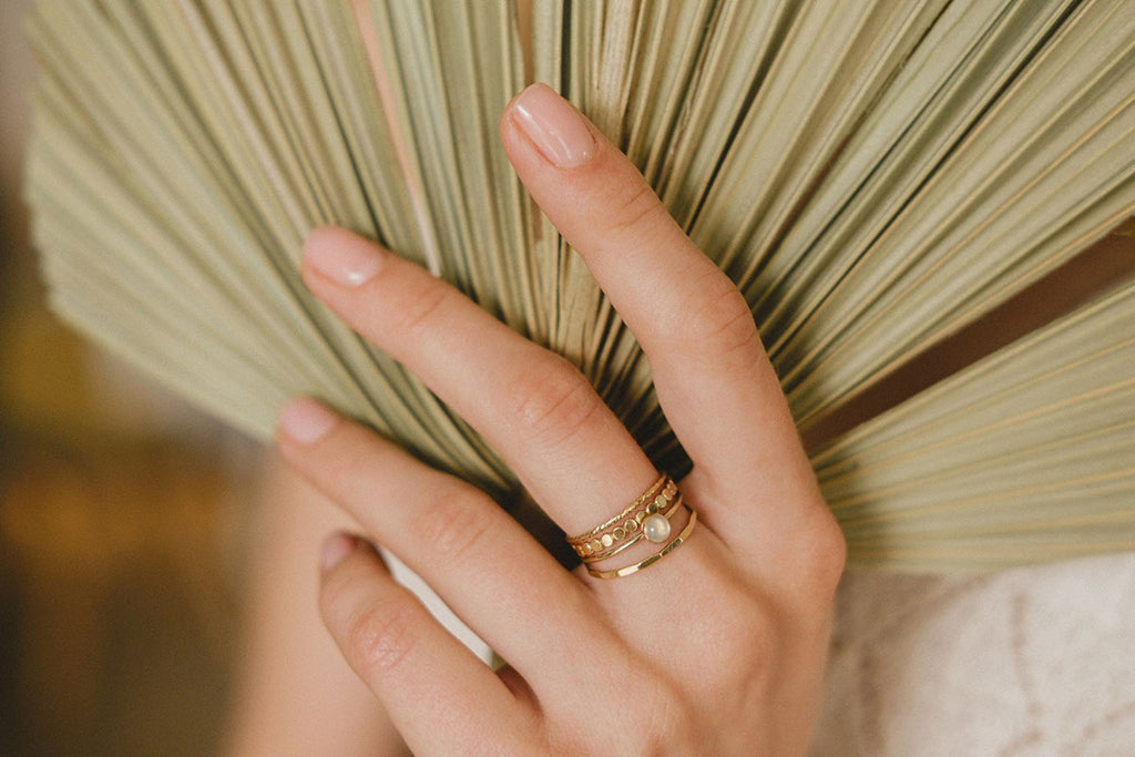 A woman's hand wearing the Malaysia rings, a stack designed, made, and curated by Zoaje. 