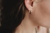 A woman wearing delicate gold hoop earrings. 