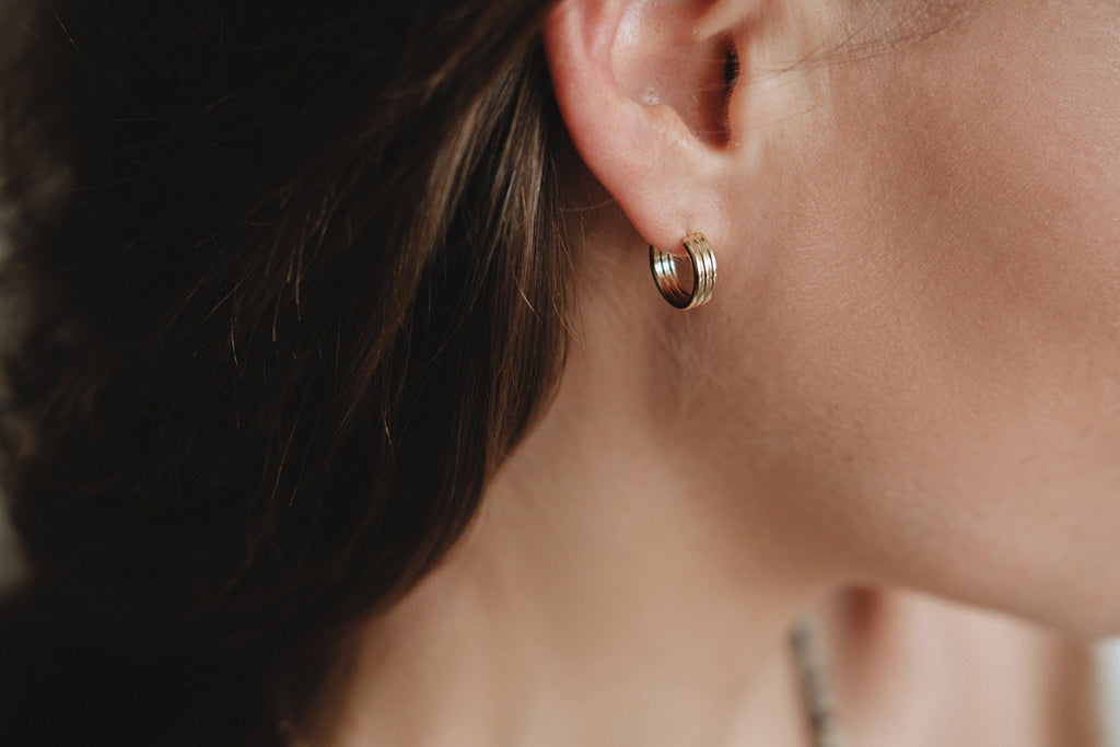 A woman wearing delicate gold hoop earrings. 
