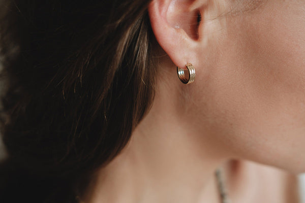 A woman wearing delicate gold hoop earrings. 