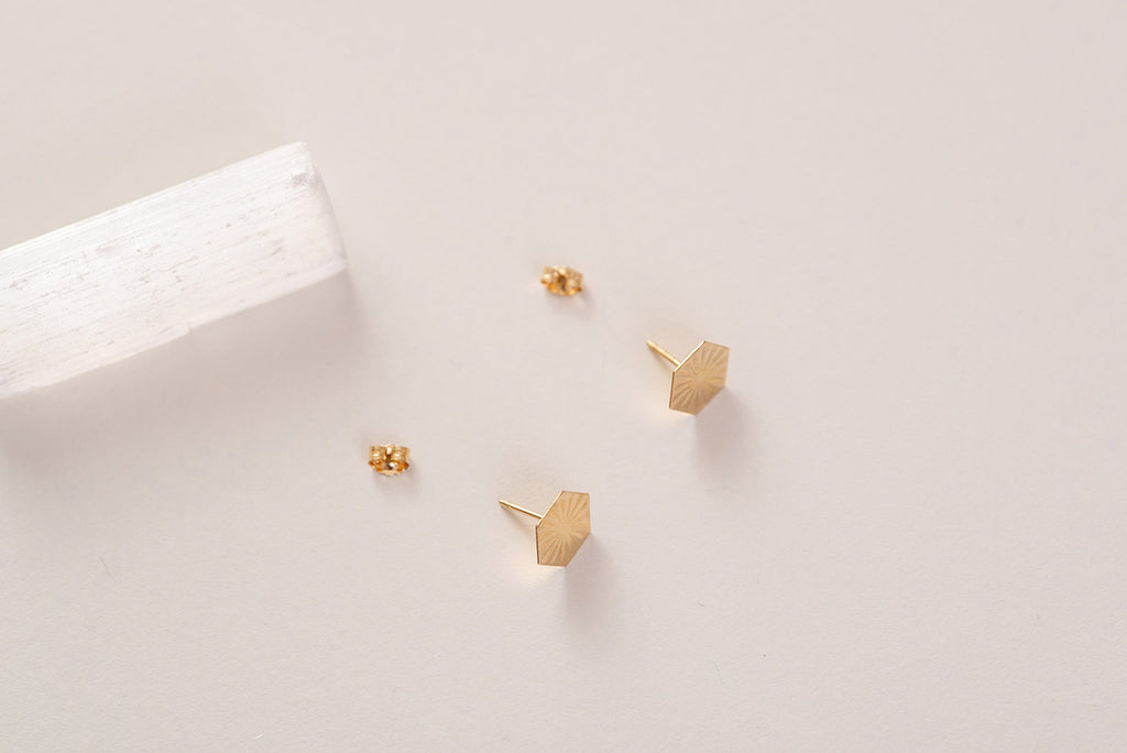 A top down view of the Nepal hexagon studs, in yellow gold-fill with butterfly backs. 