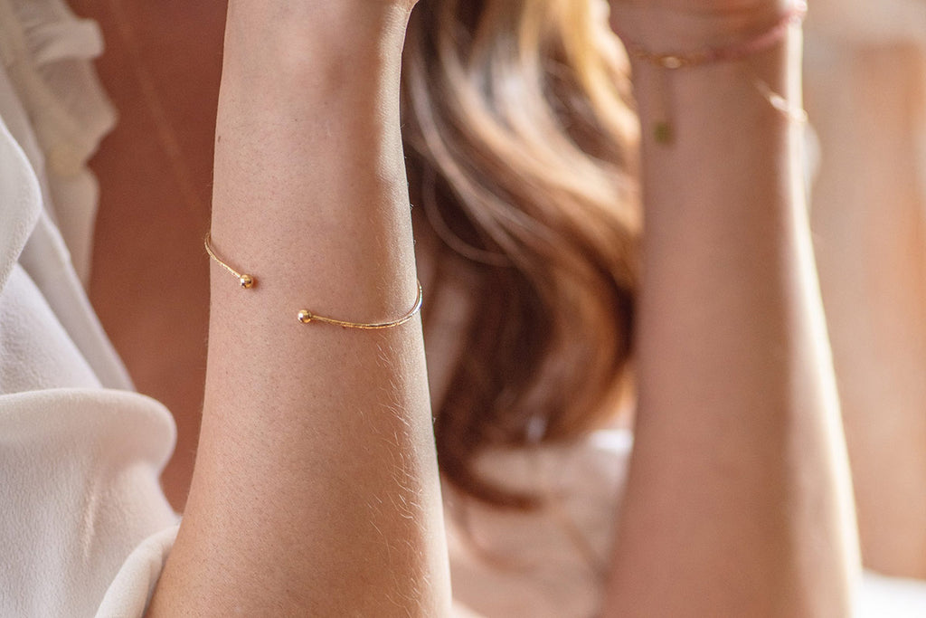 A woman wearing the Denmark bracelet, a bangle style cuff that works brilliantly as part of a stack or by itself. 