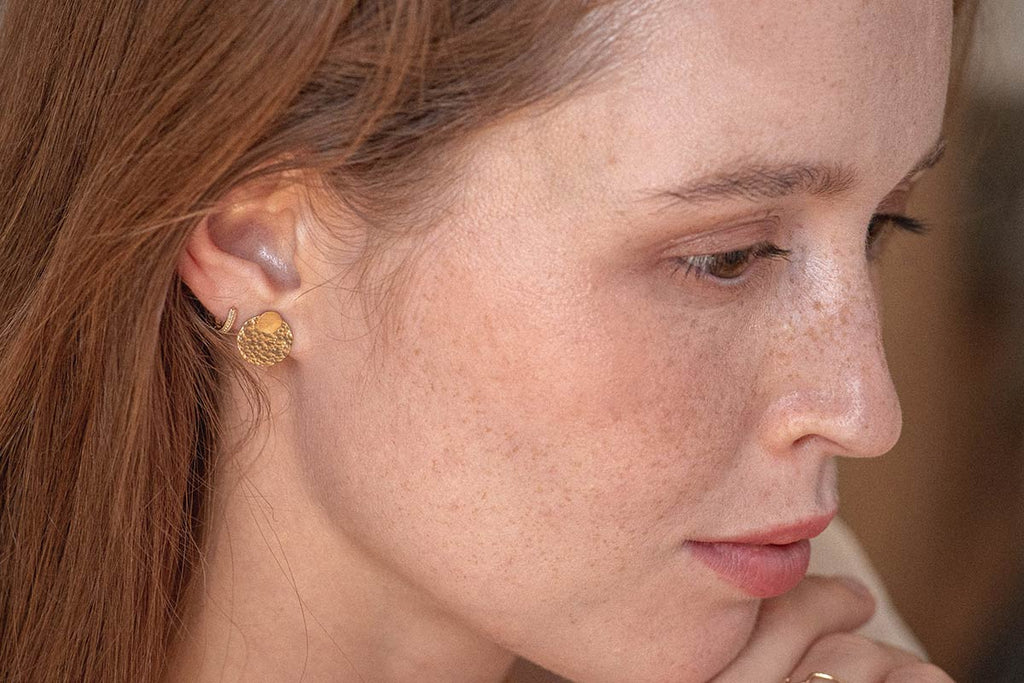 A woman wearing Zoaje's designer jacket stud earrings in yellow gold. 