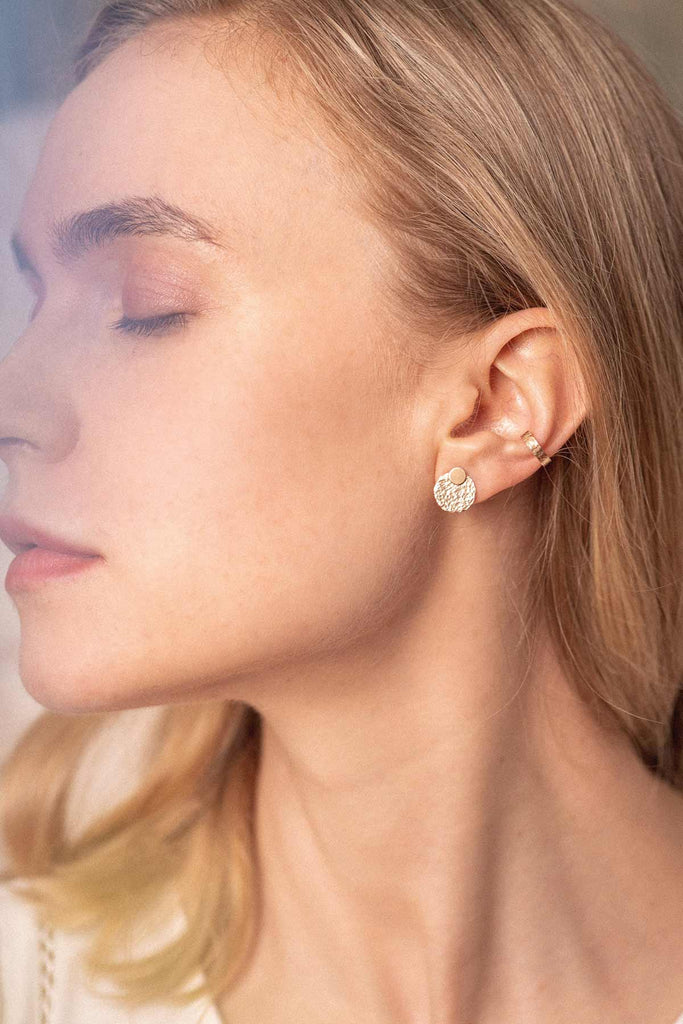 A woman wearing gorgeous hammered gold-fill round stud earrings. 
