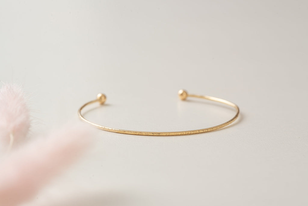 A beautiful hammered gold-fill bangle, lying on it's side. 