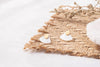 Zoaje designer earrings, displayed on a grass mat, to showcase the textures of the earring. 