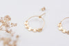 A close up view of two gold hoop earrings with stud backs, with five gorgeous tiny brushed metal discs as charms at the centre. 