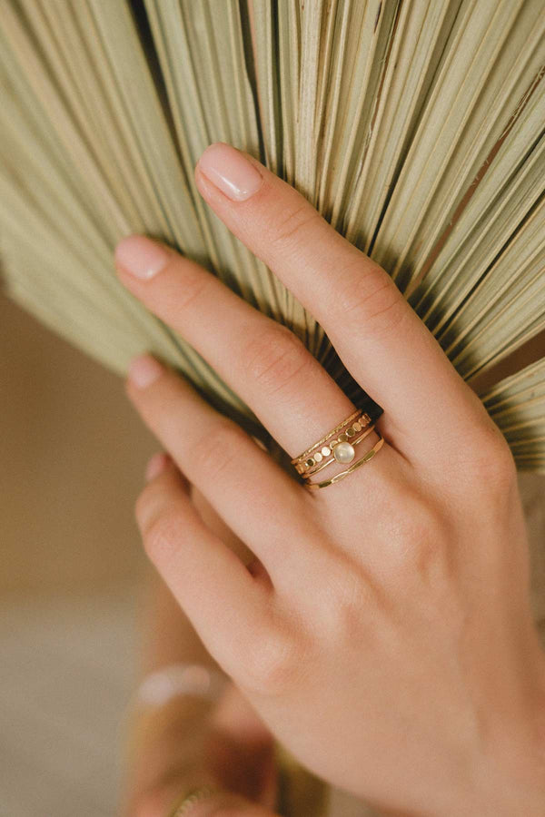 A woman's hand wearing the Malaysia ring stack, a set of four beautiful gold-fill rings. 
