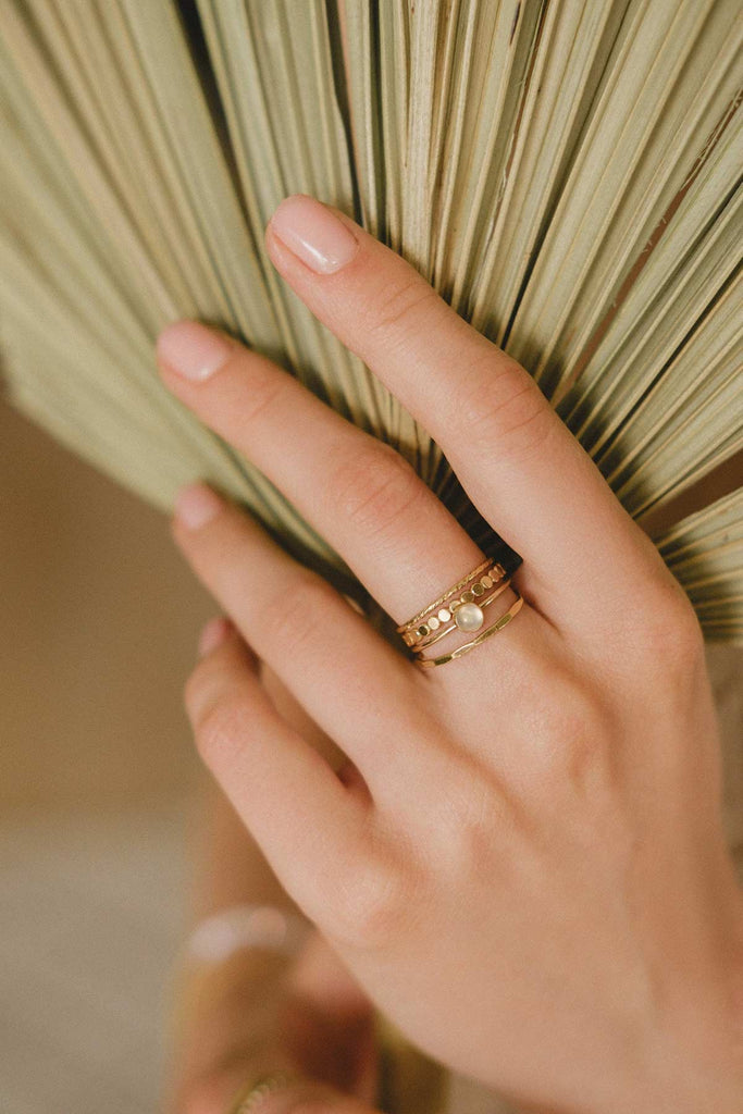 A woman's hand wearing the Malaysia ring stack, a set of four beautiful gold-fill rings. 