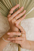 A woman's hands wearing a number of curated ring stacks by Zoaje, including the Malaysia stack (bottom). 