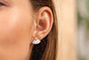 A woman wearing gold-fill and mother-of-pearl geometric stud earrings. 