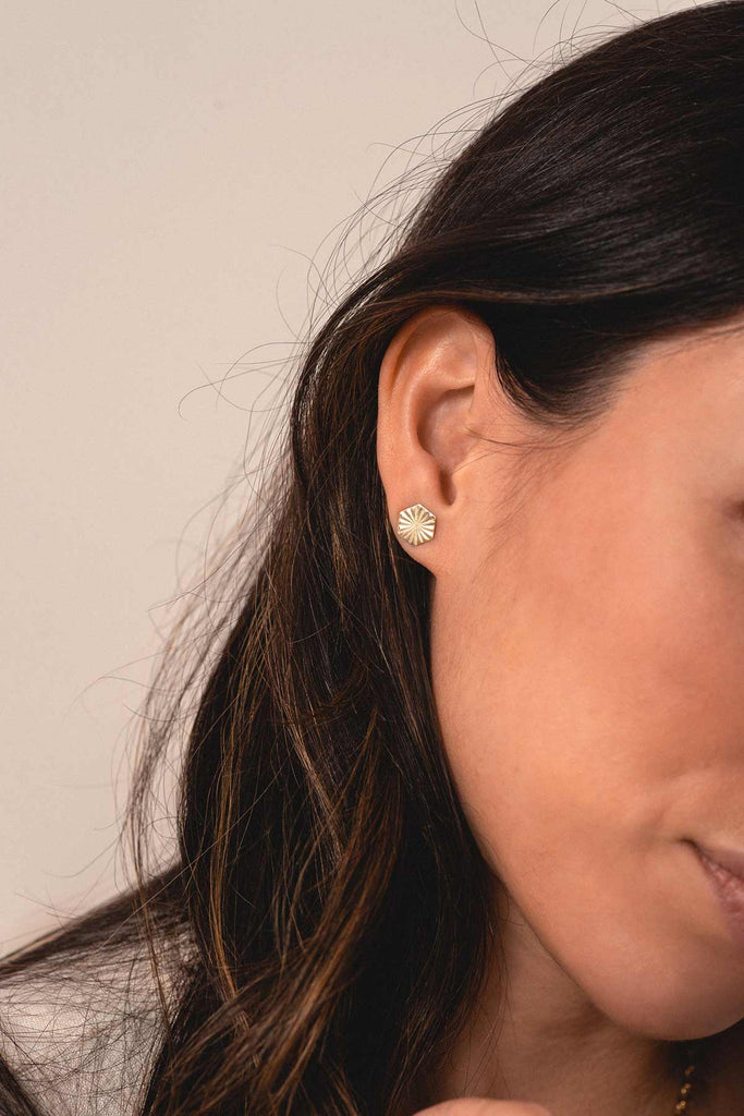 A woman wearing the hexagonal studs with a starburst pattern by Zoaje.