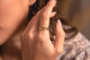 A woman wearing a delicate stack of three rings, with gold fill and a feature of natural labradorite