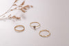 The three rings that make up the Cambodia ring stack, seperated so they're all individual. One is made of a wiggly line, one is small hammered circles, and one is a simple ring with a feature crystal made of natural labradorite. 
