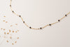 A delicate chain link necklace made with yellow gold, interspersed with black agate beads. 