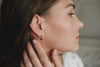 A woman wearing slightly thick, small, yellow gold hoop earrings by Zoaje. 