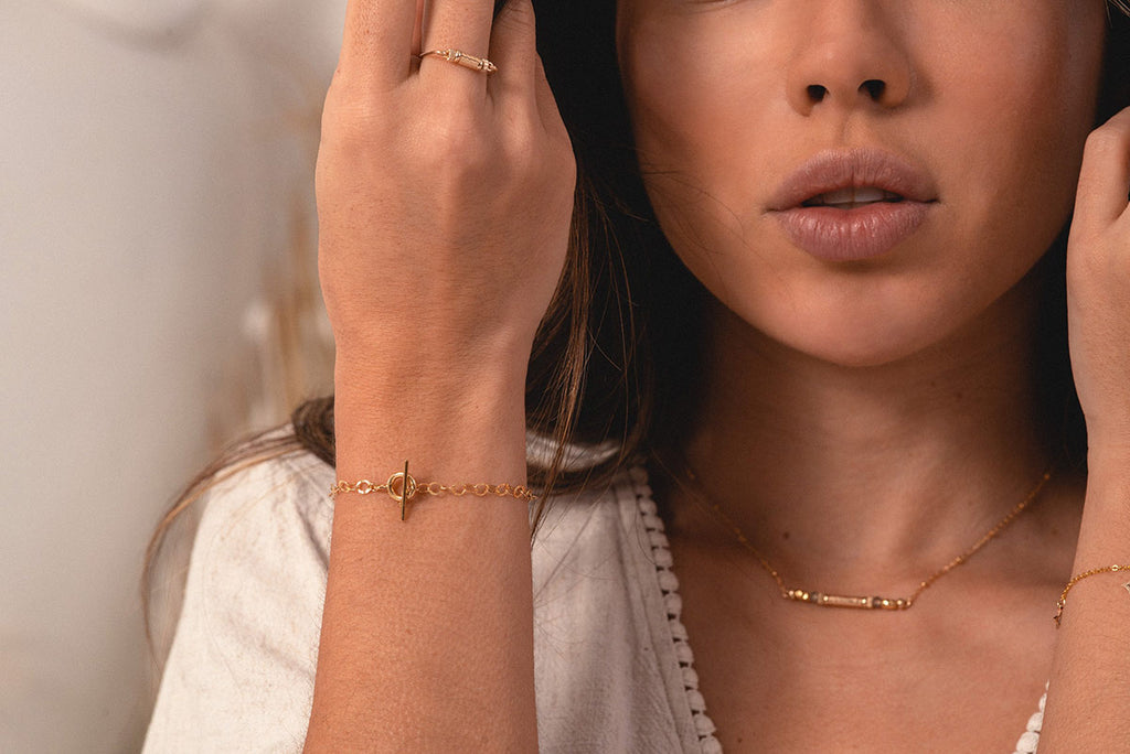 A woman's arm, displaying the hammered golden chain of the Thailand bracelet by Zoaje. 