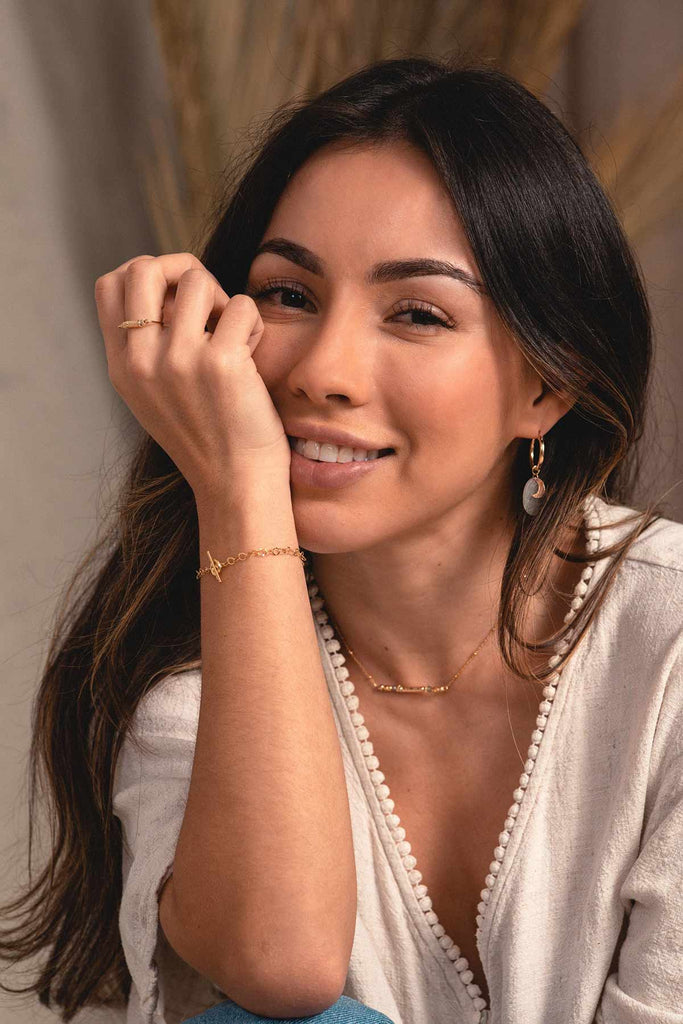 A woman wearing an elegant chain link bracelet made of yellow gold, with an OT clasp.