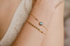 A woman wearing two dainty chain link style bracelets in 100% yellow gold fill. 