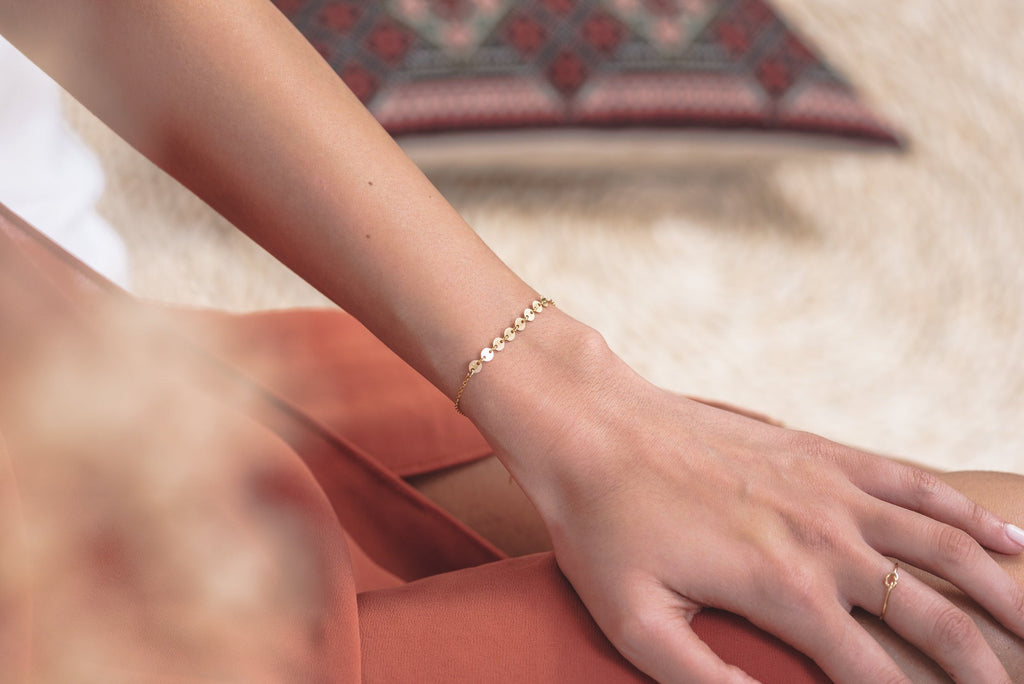A woman wearing the Italy bracelet by Zoaje, a delicate sophisticated chain with round pieces in hammerd yellow gold. 