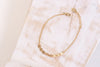 A delicate chain style bracelet in yellow gold with small round charms. 