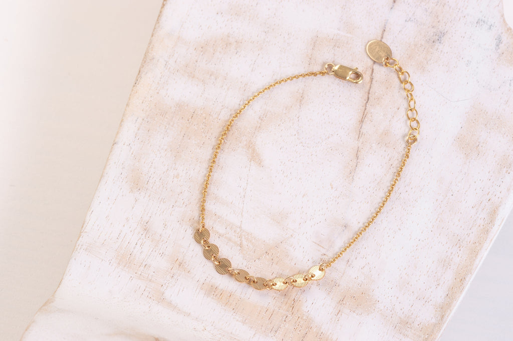 A delicate chain style bracelet in yellow gold with small round charms. 