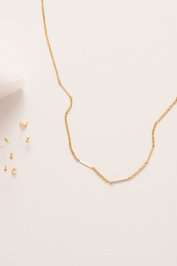 A fine delicate gold chain necklace with flattened sections giving texture. 