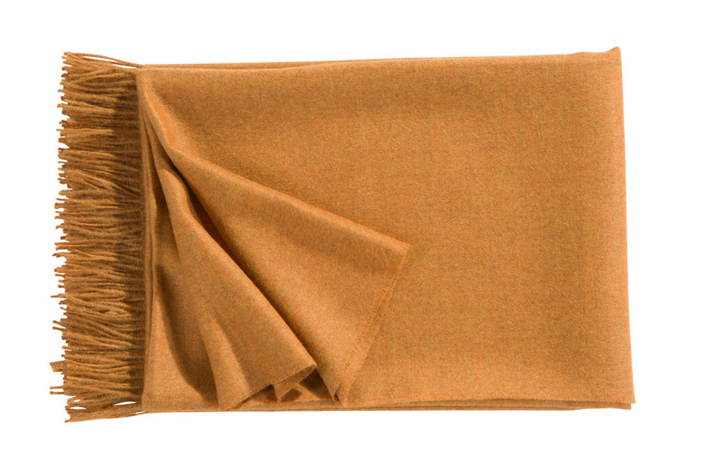 A luxurious Christian Fischbacher throw with fringe detail, made from soft warm alpaca yarn, and in a fashionable amber orange-yellow shade