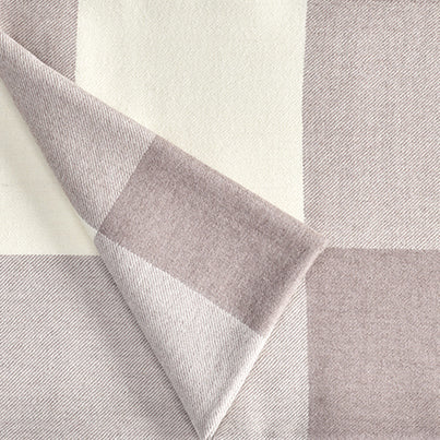A close up of a luxurious Christian Fischbacher throw, made from soft warm alpaca yarn, and in a beautiful dusky-pink and white plaid