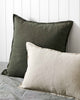 Weave linen como cushions in khaki green and linen, sitting on a bed against a wall. 