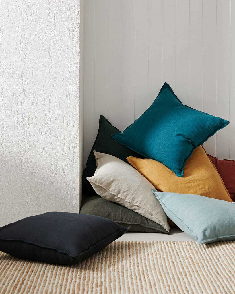 Beautiful pile of Weave Home NZ linen cushions in the corner of a white room