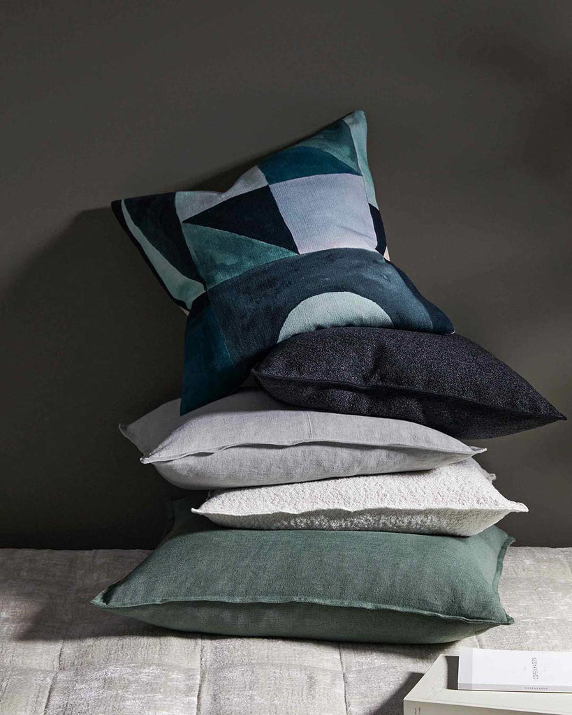 Stack of Weave Home NZ cushions against a wall in a styled room interior