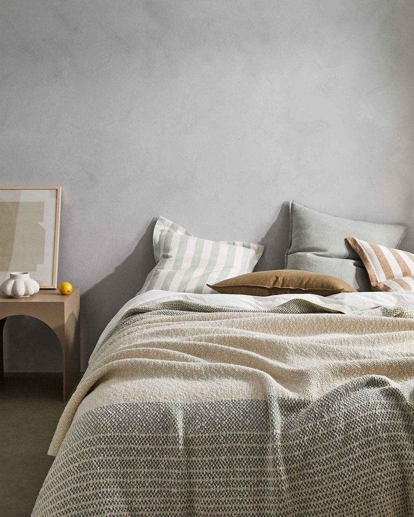 A modern bedroom setting featuring some striped and plain  linen cushions, by Weave Home NZ