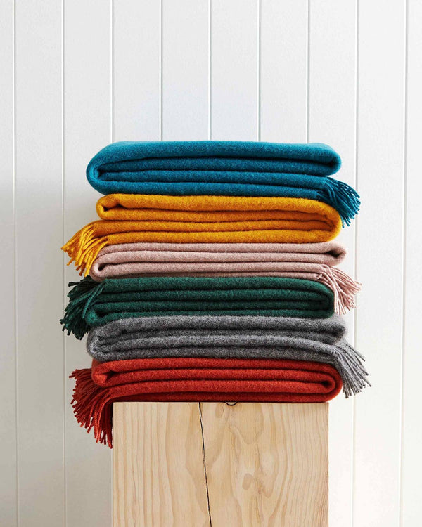 A beautiful stack of NZ lambswool throws in on-trend jewel tones; by Weave Home NZ