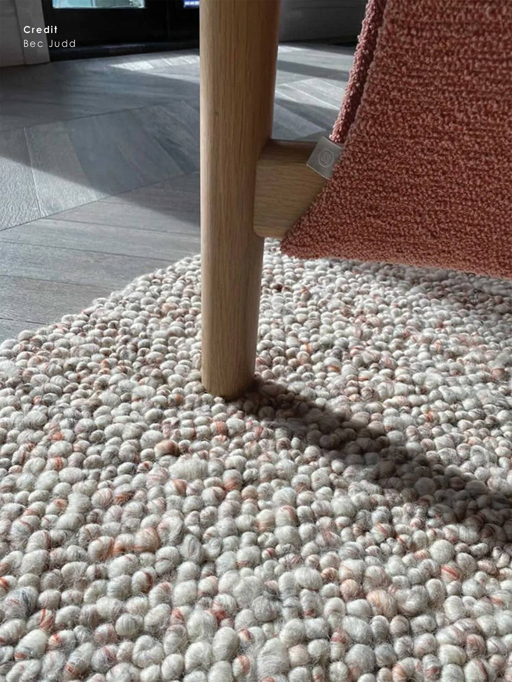 The Tribe Home NZ bobbly wool rug in colour coral under a chair close up