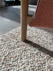 The Tribe Home NZ bobbly wool rug in colour coral under a chair close up