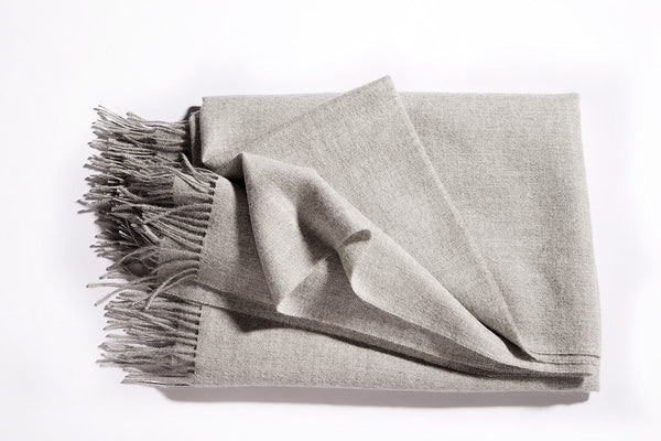 A luxurious Christian Fischbacher throw with fringe detail, made from soft warm alpaca yarn, and in a sophisticated and versatile soft grey colour