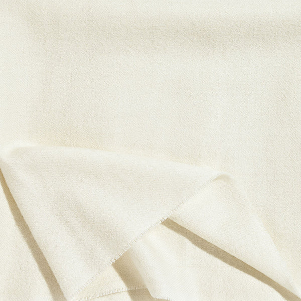 A close up of a luxurious Christian Fischbacher throw, made from soft warm alpaca yarn, and in a beautiful cream