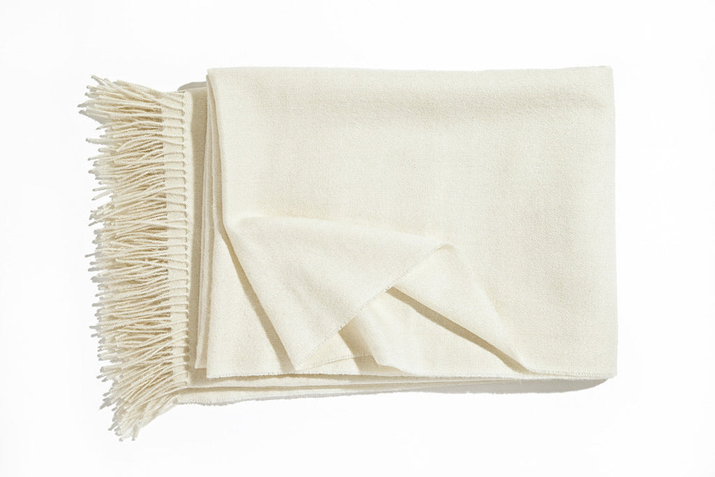 A luxurious Christian Fischbacher throw with fringe detail, made from soft warm alpaca yarn, and in a beautiful cream