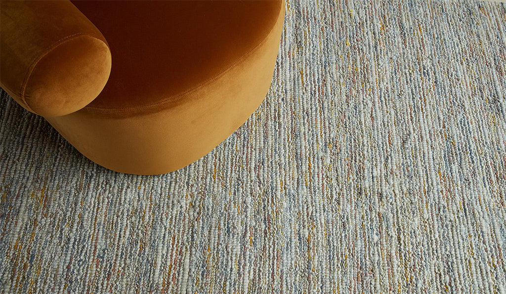 The Tribe Home NZ ridge woollen floor rug seen under an orange-mustard coloured chair