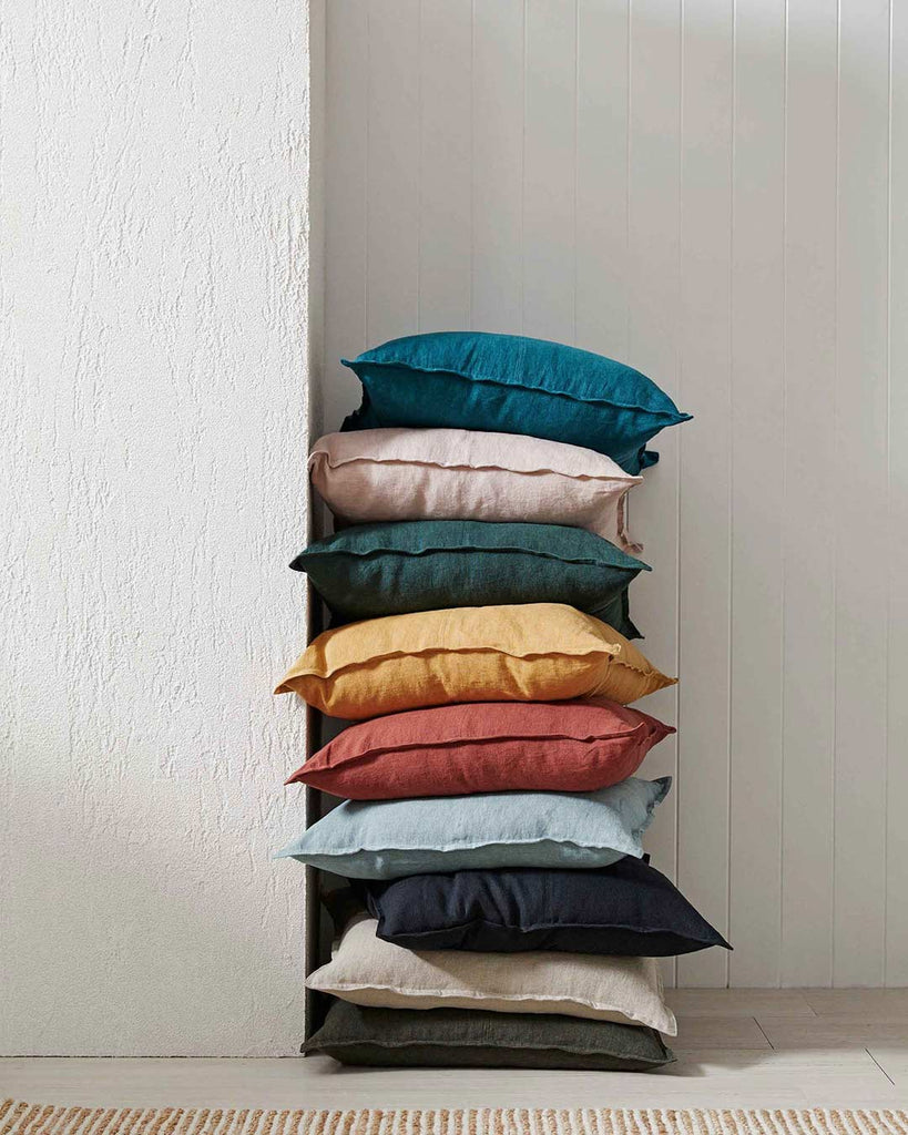 Stack of jewel toned Weave Home Como Linen cushions in a room against a wall 