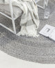 Detailed view of chair and book atop a grey-toned PET recycled fibre outdoor rug by Baya NZ