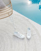 An outdoor rug in shades of cool white by Baya NZ, sitting by a swimming pool with a pair of white shoes on top of it. 